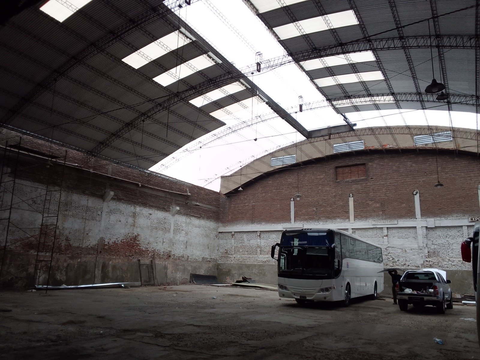 amplo interior industrial com ônibus estacionado — projeto Galpon en Avellaneda, por Arquitecto Guido Niccoli, em Avellaneda